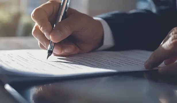 business man's hand holding pen over a construction contract